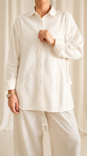 Person wearing a white shirt and pants against a neutral background