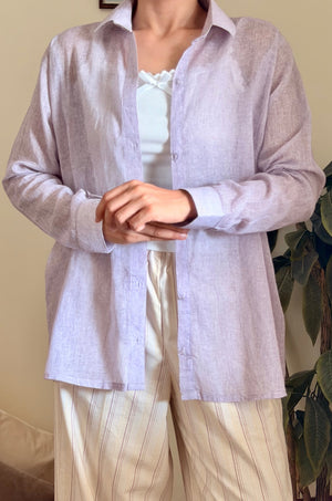 Person wearing a light purple shirt and white pants indoors.