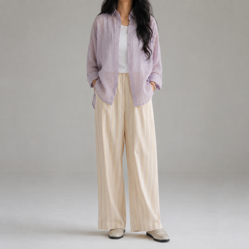 Person wearing a light purple shirt and beige pants on a plain background